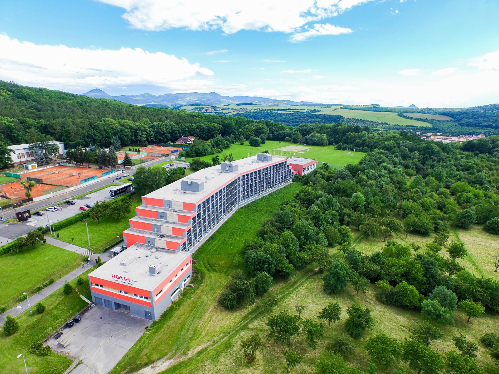 Ein Hotel in einer grünen Hügellandschaft mit Tennisplätzen und Sportanlagen in der Nähe, ideal für Tenniscamps.